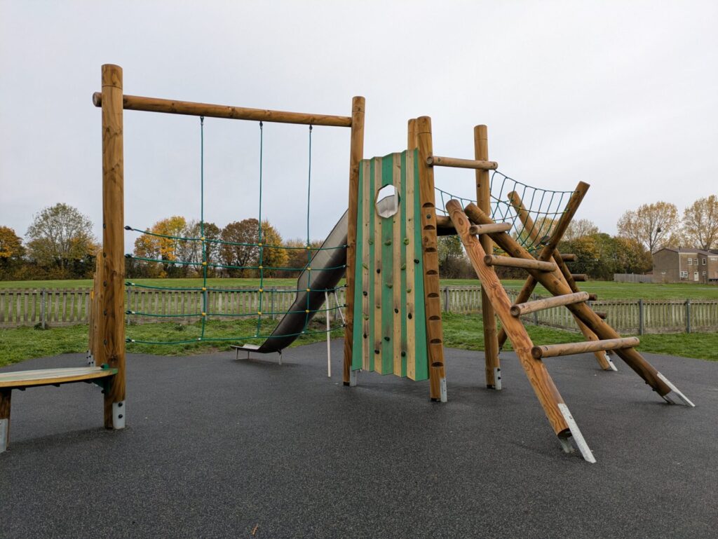 A wooden playground structure featuring a slide and swings, designed for children's outdoor play and recreation.